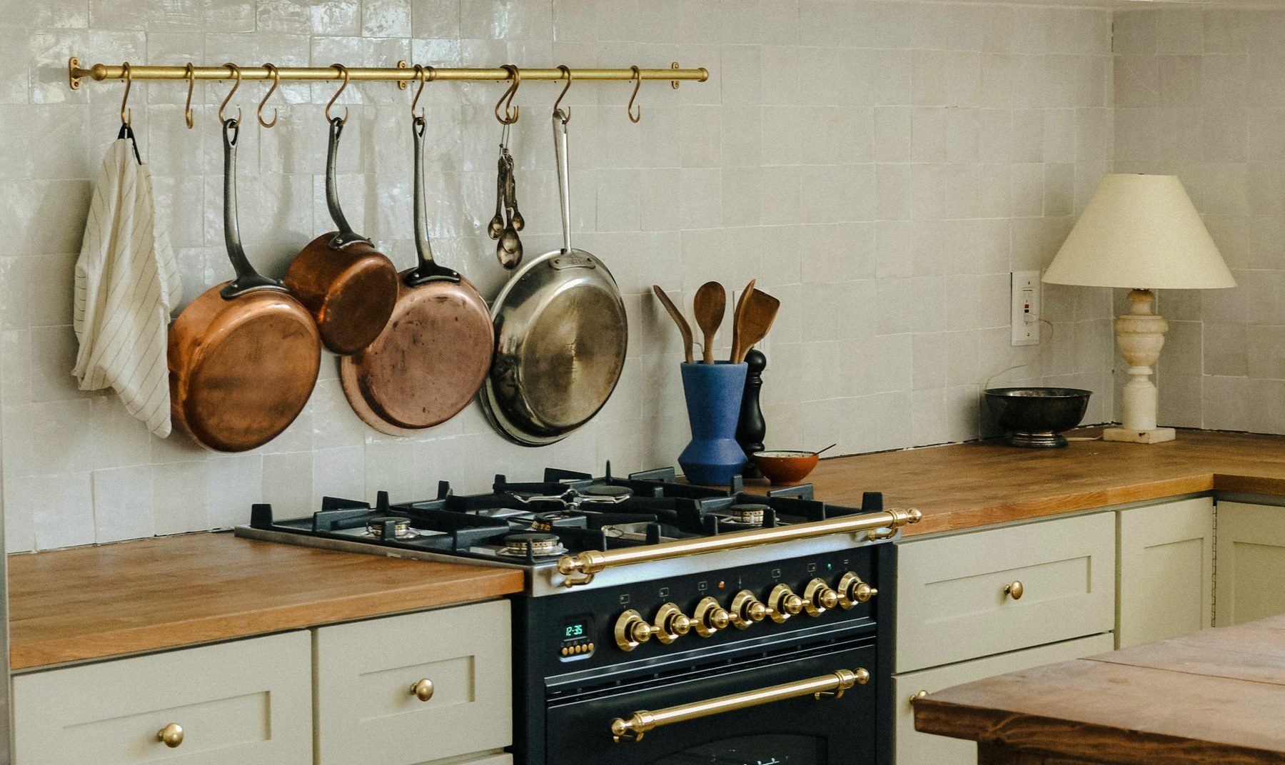 A black and brass range with hanging copper pans.